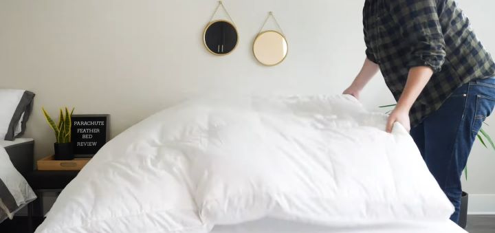 A tester puts the mattress topper on the bed to check its quality and size